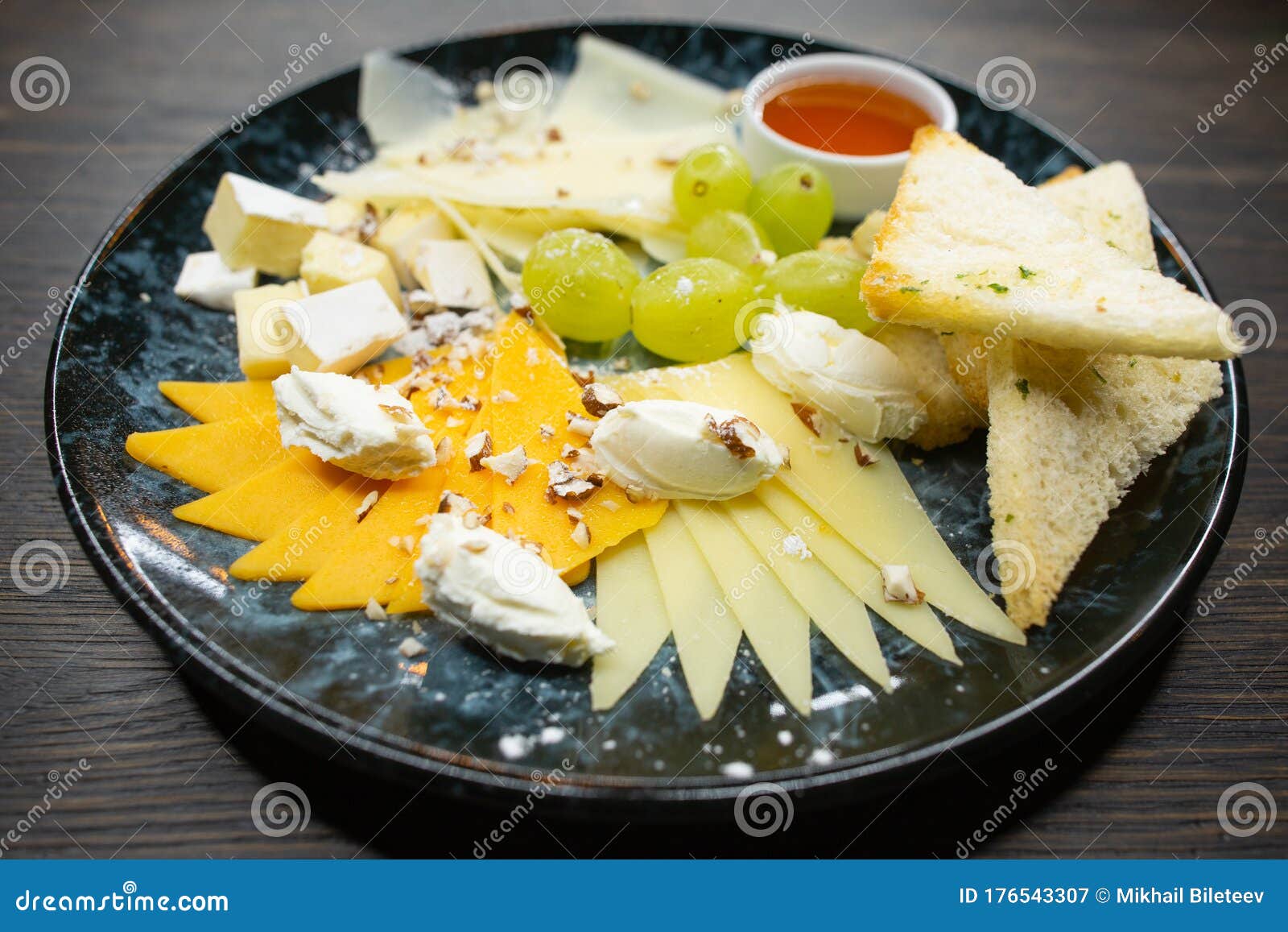 assorted cheese. thin sliced Ã¢â¬â¹Ã¢â¬â¹cheese with grapes crispy croutons of white bread with honey